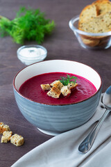 grey bowl of soup.vegetable soup with greens and croutons. bowl of Beetroot cream soup with bread and white cream on a wooden background. Healthy diet lunch with copy space. vertical