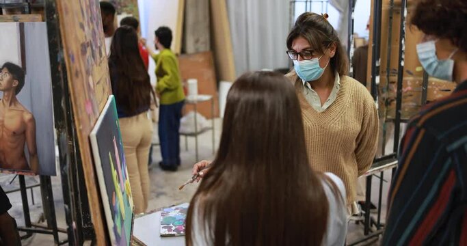 Young students painting inside art room class wearing safety masks