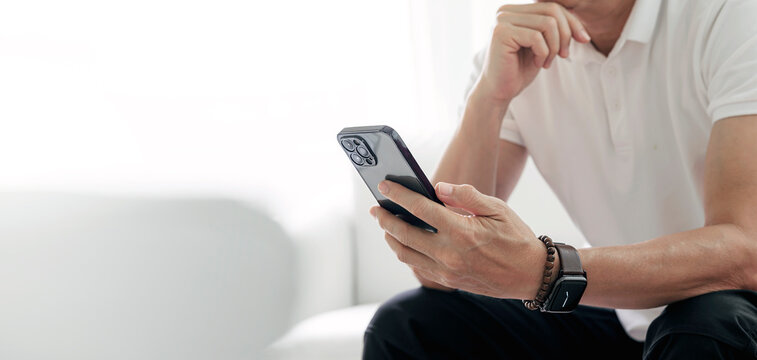 Young man with smartphone in his hands. Modern businessman using smartphone at home. Cropped image with copy space.