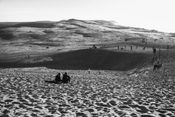 Unrecognizable people relaxing on Dune of Pilat, tallest sand dune in Europe. Arcachon bay, France. Black white historic photo.