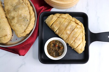 Himachal Pradesh special dish siddu. It's a steamed wheat flour bread stuffed with split black gram lentils, dry fruits, poppy seeds, walnut etc. Served with ghee and tomato chutney. Copy space