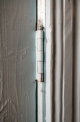 Metal hinge on a wooden painted door indoors, in a rural house. Country style. 