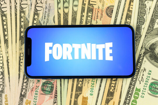 Fortnite logo on Apple iPhone screen. Backgound of money, dollar bills, top view business photo