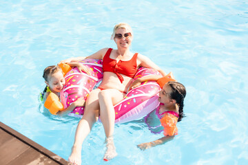 Happy family in the pool, having fun in the water, mother with kids enjoying aqua park, beach resort, summer holidays, vacation concept