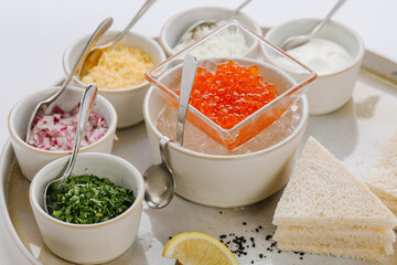 Dish with red caviar and herbs on white background