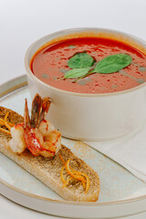 Tomato soup with tiger prawns on a white background