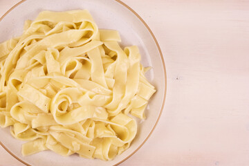 Fettuccine Alfredo. Fettuccine with cheese and butter sauce, portion in a plate, top view, copy space