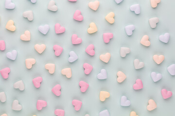 Composition with candy hearts on pastel blue background.