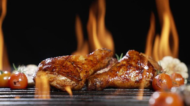 Chicken drumsticks grilled on hot barbecue charcoal flaming grill. Juicy chicken meat roasted on bbq grill. slow motion