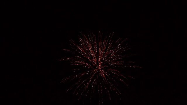 Handheld slow motion shot of a sky shot firecracker bursting against the black sky at night. Firecracker in the sky during festival. Fireworks in the sky background for celebration of holidays. 