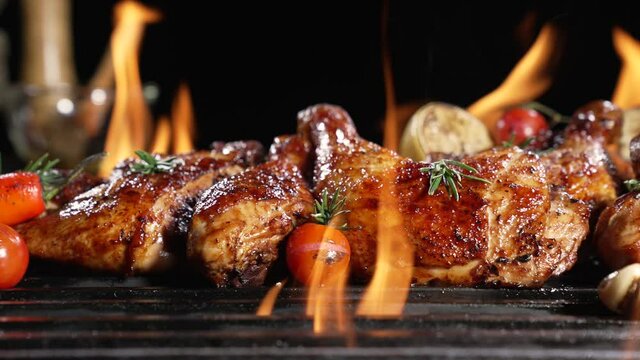 Chicken drumsticks and thighs grilled on hot barbecue charcoal flaming grill. Juicy chicken meat roasted on bbq grill. slow motion