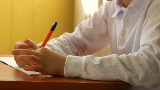 Close-up of the hand of a left-handed schoolboy learning to write. Caucasian left-handed child writes in a notebook doing homework. A preschooler child learns to write with a pen. selective focus