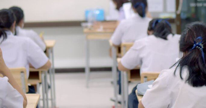 Asian high school students in a white school uniform wearing the masks to do final exams in the midst of Coronavirus disease 2019 (COVID-19) epidemic.