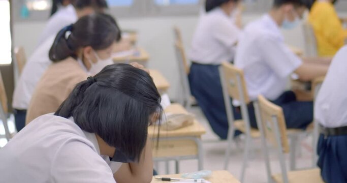 Asian high school students in a white school uniform wearing the masks to do final exams in the midst of Coronavirus disease 2019 (COVID-19) epidemic.