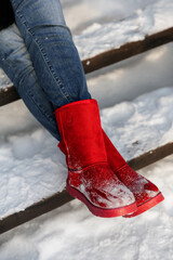 red ugg boots in the snow. street in winter and shoes on your feet.