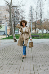 Obraz premium Stylish woman wearing warm clothes and a hat while walking down the street.