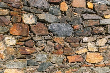 Background of stones. A wall of multicolored stones. Old masonry. An old wall of large stones.
