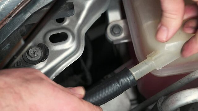 Close-up footage on a rubber hose inside a car's engine compartment as it is reconnected by slipping it into the seat and applying the clamp. Concept of repair and maintenance, do it yourself.