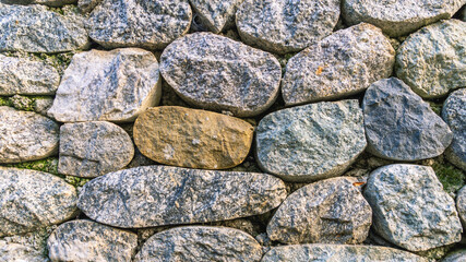 Background of stones. A wall of multicolored stones. The masonry is made of untreated stones. A wall of large stones.