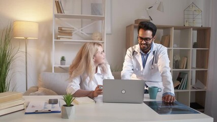 Medical colleagues. Research information. Friendly communication. Smiling man and woman looking laptop talking together in light clinical room interior.