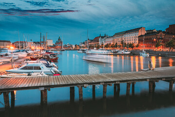 Naklejka premium Embankment At Summer Evening In Helsinki, Finland. Town Quay, Famous Place HELSINKI, FINLAND. Evening dusk view to marina In Helsinki, Finland. Town Quay.