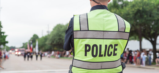 Panoramic close-up rear view police officer at public July 4 parade street event near Dallas,...