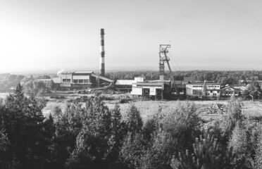 Fototapeta na wymiar Beautiful, black and white, view on coal mining 'Boze Dary' in Katowice, Silesia, Poland seen from mining heap at sunrise. Nature versus industry. A mine surrounded by forest.