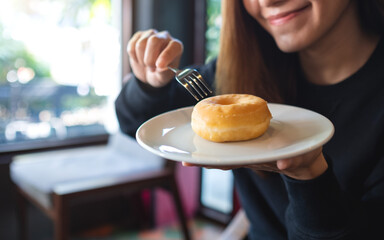 Closeup of a young woman holding and eating donut