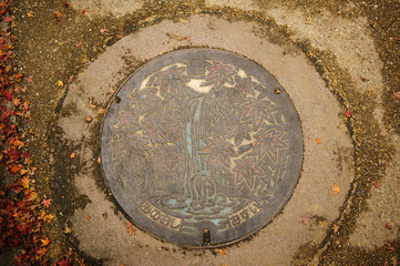 Minoo Falls and maple leaves painted on a manhole cover in Minoo City