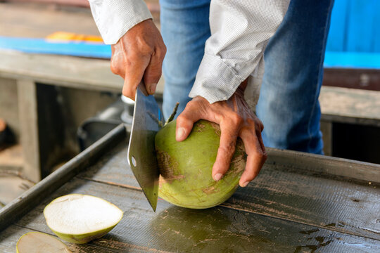 person slicing an coconut