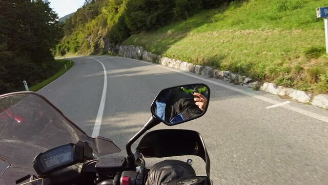 POV Biker rides a motorcycle on a scenic sunny mountain road, Austria. Steering wheel view. Motorcyclist on Motorbike goes between mountain valley by landscape highway. First-person view. Moto trip.