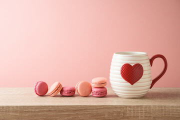 Valentines day concept with coffee cup, heart shape and macaroons dessert on wooden table over pink...