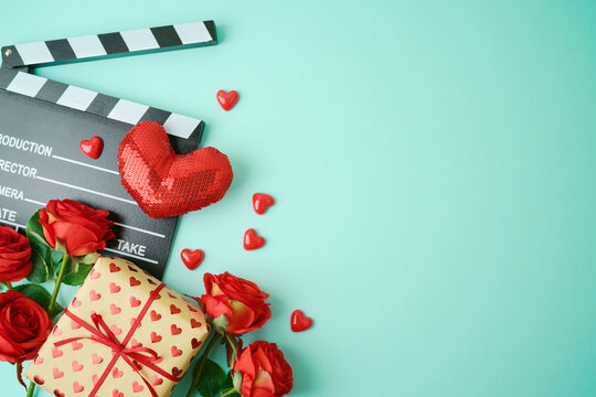 Valentines day background with movie clapper board, heart shapes and gift box. Romantic movie concept. Top view with copy space