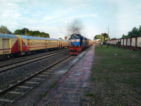Indian Train Departing from station with black smoke chugging out from Engine.