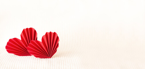 two red paper corrugated hearts on a warm knitted background. High quality photo