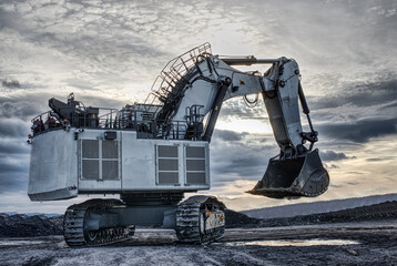 Big excavator in coal mine at cloudy day