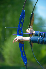 professional archers shooting with modern longbows at meadow