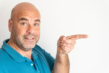 Portrait of middle-aged Caucasian man smiling, looking at camera and pointing to the right with his index finger, on white background.