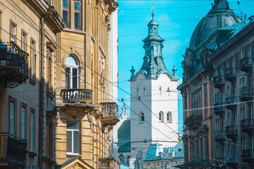 view of lviv street with cathedral church tower between buildings
