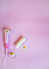 Menstrual tampons and chamomile on pink background.