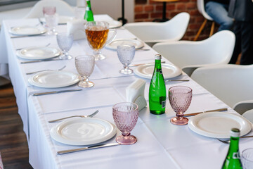 Table setting with white tablecloth, plates and cutlery laid out.