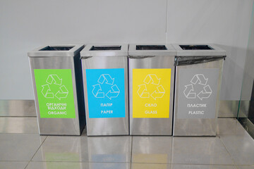 Colored rubbish containers for separate sorting of garbage. Containers for recycling various types of waste plastic, glass, paper, garbage near a white wall.