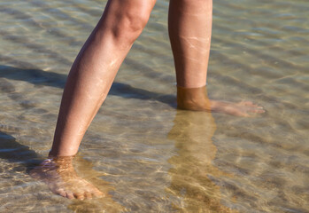 Womаn feet in the water on the sea coast