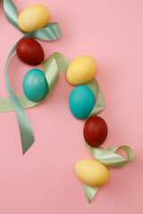 Colorful Easter eggs with green ribbons on pink background 