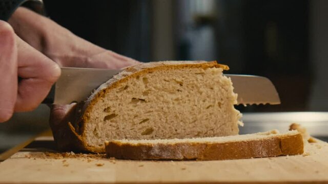 Close Up of freshly baked bread being sliced with a bread knife in Slow Motion.