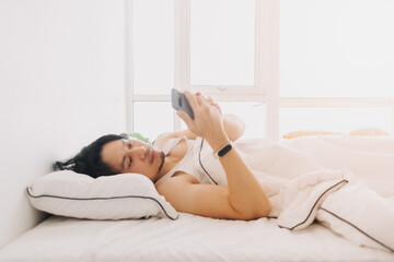 Asian man just wake up and use smartphone first thing in the morning.