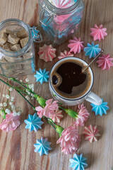 Coffee with flowers and meringues on a wooden а tray