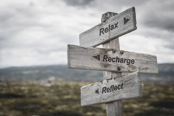 relax reflect recharge text on wooden sign outdoors.