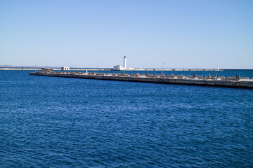 Fototapeta premium a seaport on the seashore, a lighthouse is visible in the distance, a beautiful blue sea