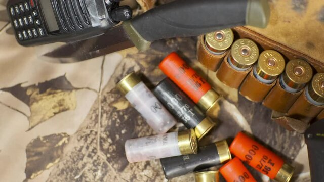 overview of shotgun cartridge belt, knife, binocular, and radio on the camouflage background
